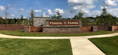 Entrance monument sign for Fendol Farms in Durham, NC, featuring stone and wood accents, landscaped greenery, and the community name displayed prominently