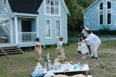 A family enjoying outdoor games in the yard of a modern blue home, representing the fun and community lifestyle offered by new construction homes in the Triangle NC